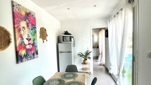 A modern kitchen with a microwave, a dining table with placemats, and a potted plant. - Bobo Chic Paradise (Villeneuve-Loubet)