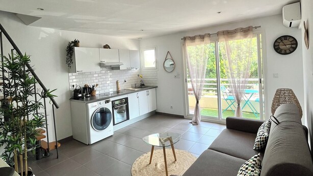A modern kitchen with a washing machine, a dining area with a sofa, and a view of the outdoors. - Bobo Chic Paradise (Villeneuve-Loubet)