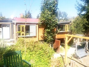 A wooden cabin with a red roof, a covered porch, and a chair. - Ferienhaus Allrode mit Wellness (Thale)