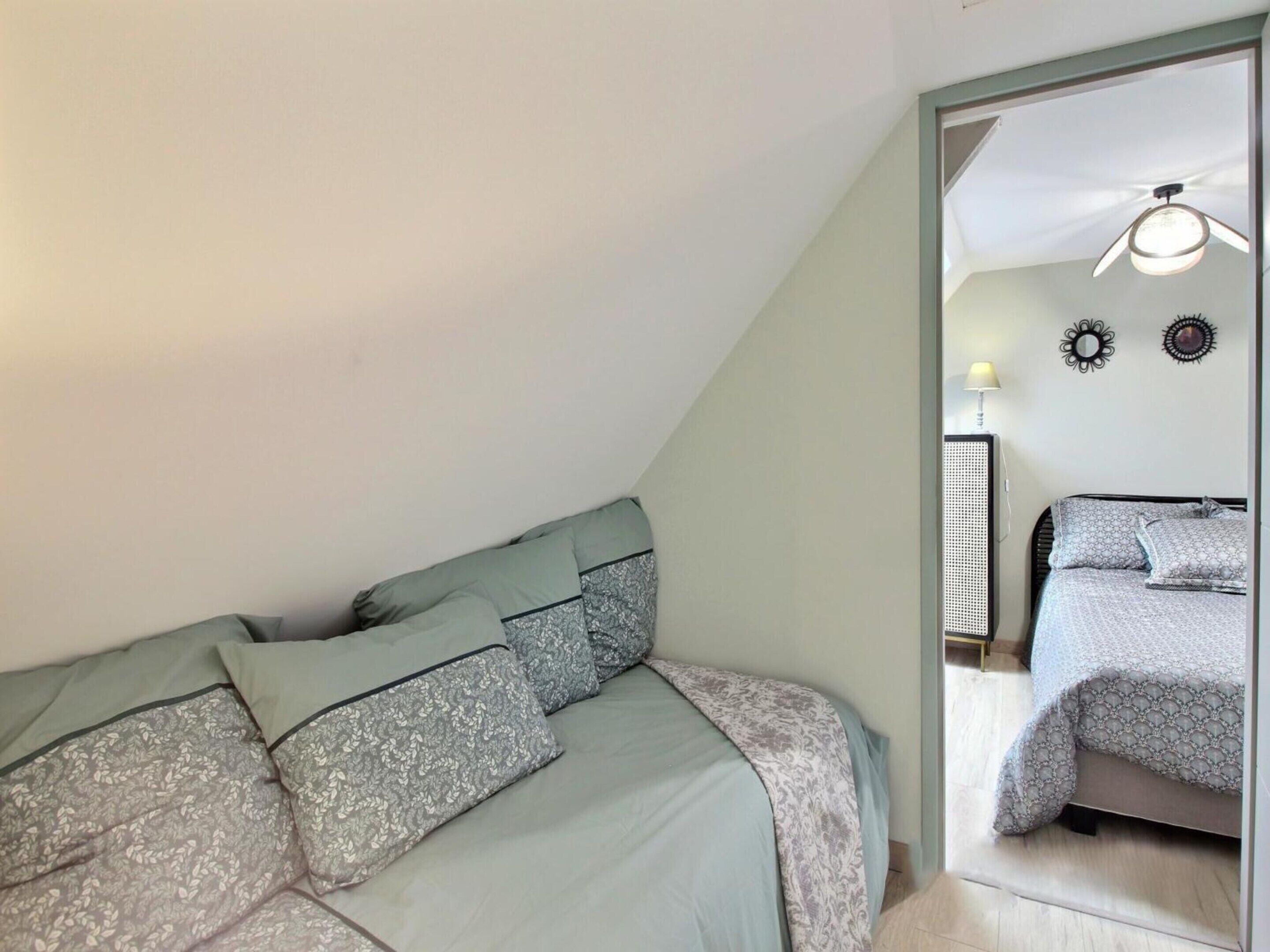 A bedroom with a bed, a ceiling fan, and a view into another room.