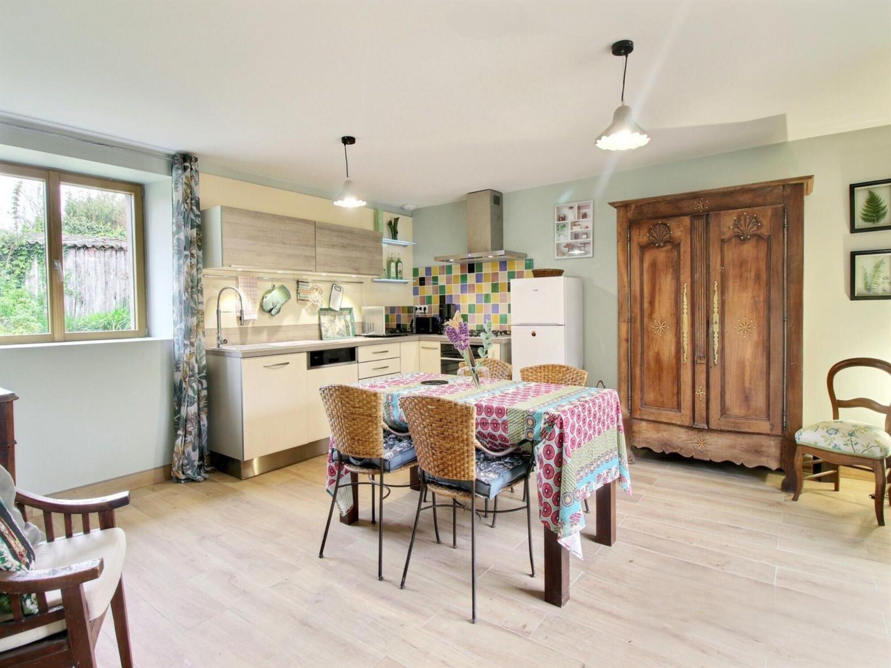 A kitchen with a dining table, chairs, a wooden cabinet, and a window with curtains.