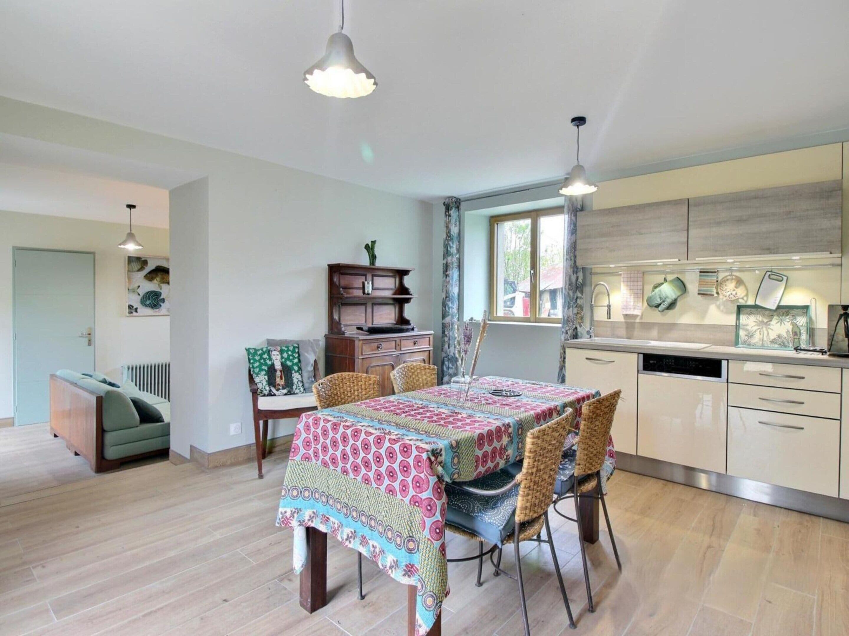 A modern kitchen with a dining area, wooden cabinets, and a window.