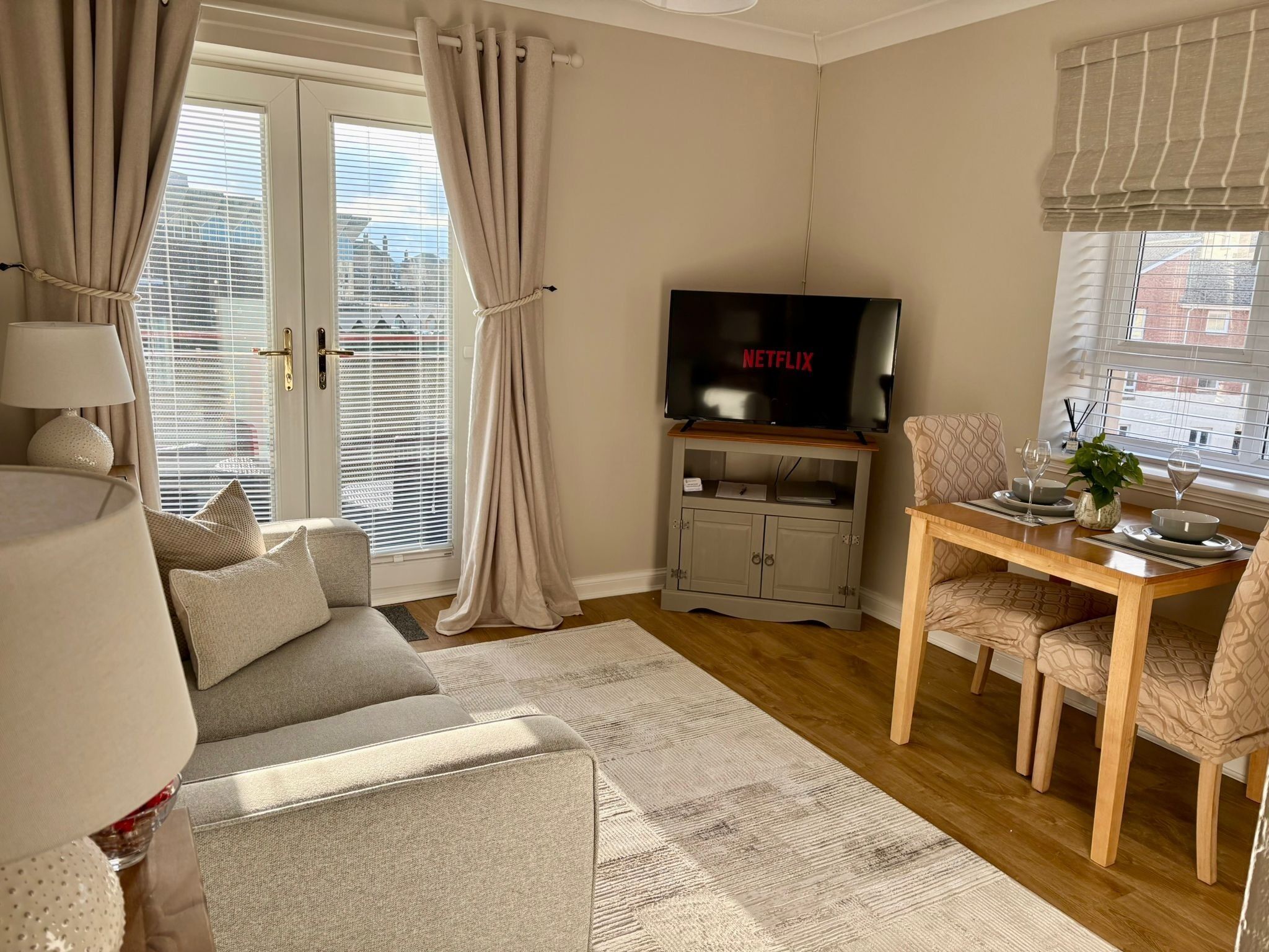 A living room with a sofa, TV, dining table, and curtains.