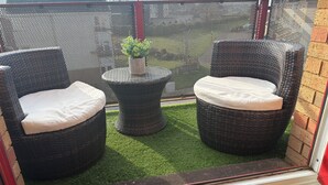 Une terrasse avec deux fauteuils en osier, une petite table et une plante en pot.