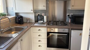 Une cuisine de taille réduite, équipée d’un évier, d’une cuisinière, d’un four et de placards.
