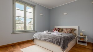 Et soveværelse med en seng, et vindue, et natbord og en vægmonteret lampe.