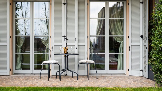 En terrasse med bord og stole, en skydedør og et lille haveområde.