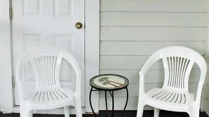 Une porte blanche, deux chaises blanches, une petite table ronde et un élément décoratif mural avec les mots «ivre » et «étendez-vous ».