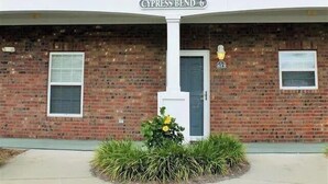 Un bâtiment à deux étages doté d’un balcon blanc, d’une façade en briques et d’une enseigne indiquant « Cypress Bend 6 ».