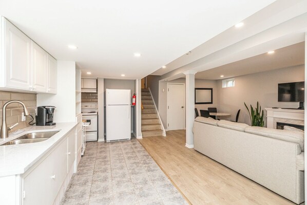 A modern kitchen with white cabinets, a built-in oven, a refrigerator, and a coffee maker.