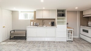 A modern kitchen with white cabinetry, a built-in microwave, and a coffee maker on the counter.