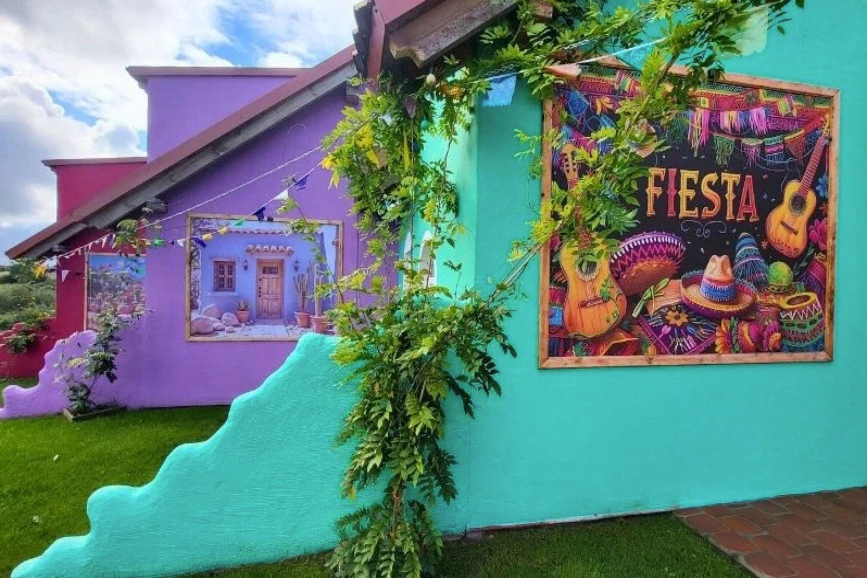 A building with vibrant exterior colors and a mural depicting a festive scene with the word 'FIESTA' prominently displayed.