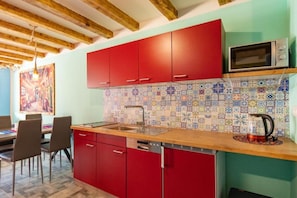 A kitchen with red cabinets, a tiled backsplash, and a microwave. - Comfortable Mexican-style Holiday Home (Ustka)