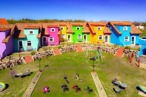 A row of colorful houses with a grassy yard, a swing set, and various children's toys. - Comfortable Mexican-style Holiday Home (Ustka)
