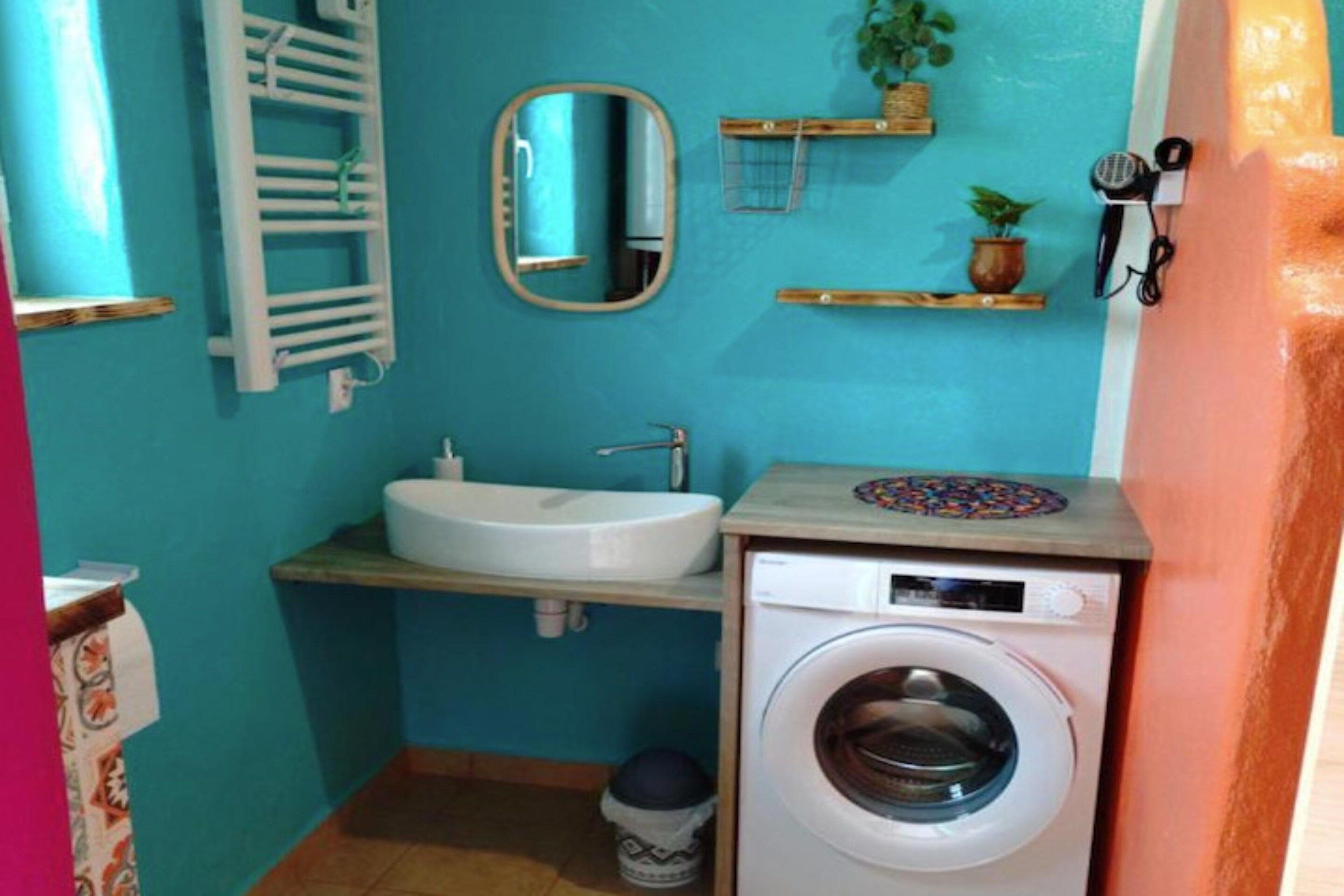 Ein kleines Badezimmer mit Waschbecken, Spiegel und Waschmaschine.