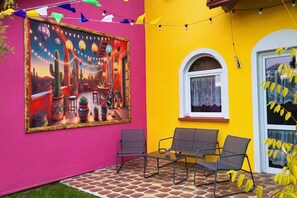 A vibrant patio area with a colorful mural, outdoor seating, and a yellow wall. - Comfortable Mexican-style Holiday Home (Ustka)