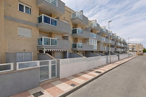 A row of modern apartment buildings with balconies, a gated entrance, and a tiled pedestrian walkway. - Pleasant Beachfront Attic Retreat (Roquetas de Mar)