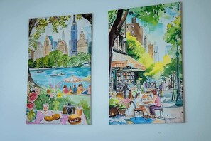 Two paintings of urban scenes with buildings, trees, and people. - Chic 1BR Ground Floor Apartment Near Centre (Cardiff)
