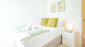 Une chambre à coucher comprenant un lit, une table de chevet et deux œuvres d’art accrochées au mur.