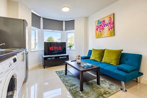 Un salon moderne avec un canapé bleu, une table basse et un téléviseur affichant le logo « NETFLIX ».