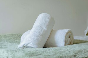 Two rolled white towels on a textured green blanket. - Chic 1BR Ground Floor Apartment Near Centre (Cardiff)
