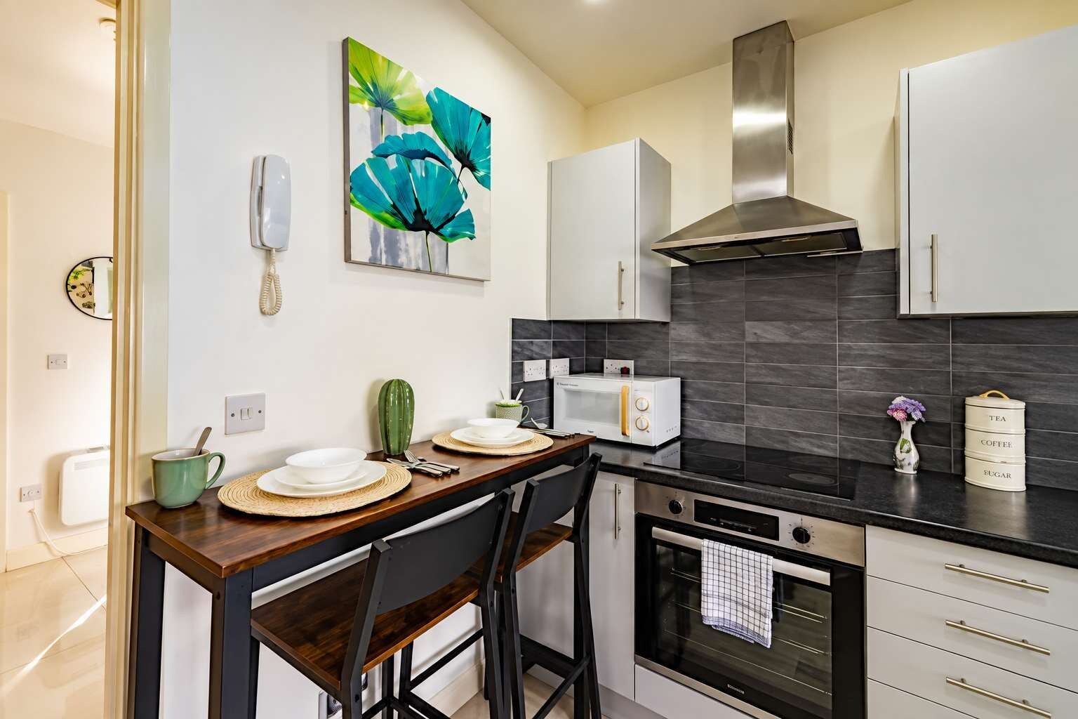 A modern kitchen with a dining table, chairs, a microwave, a stove, and cabinets.