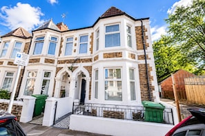 A two-story residential building with a bay window, a front porch, and a garage. - Modern 1BR Apartment, Minutes from Cardiff Centre (Cardiff)