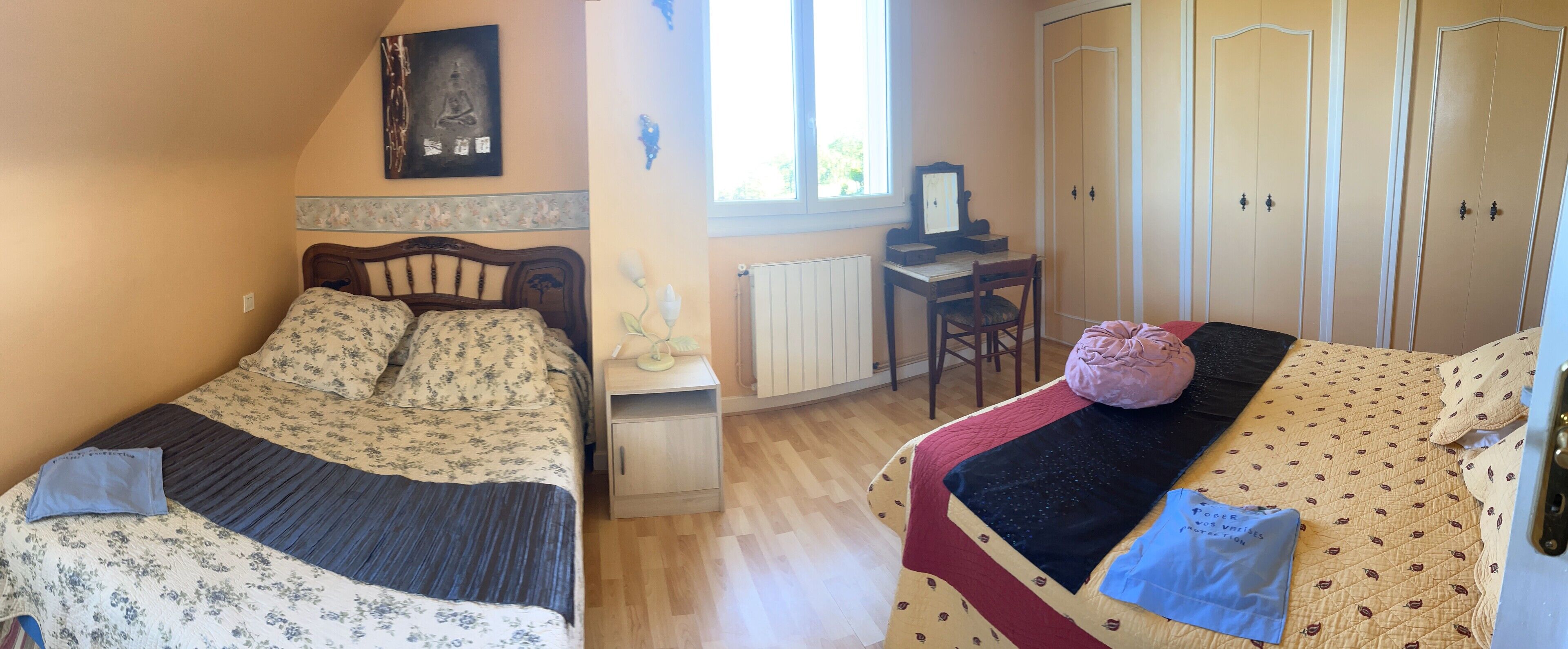 A bedroom with two beds, a desk, and a wardrobe.