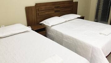 Two single beds with wooden headboards, white bedding, and a bedside table with a lamp.