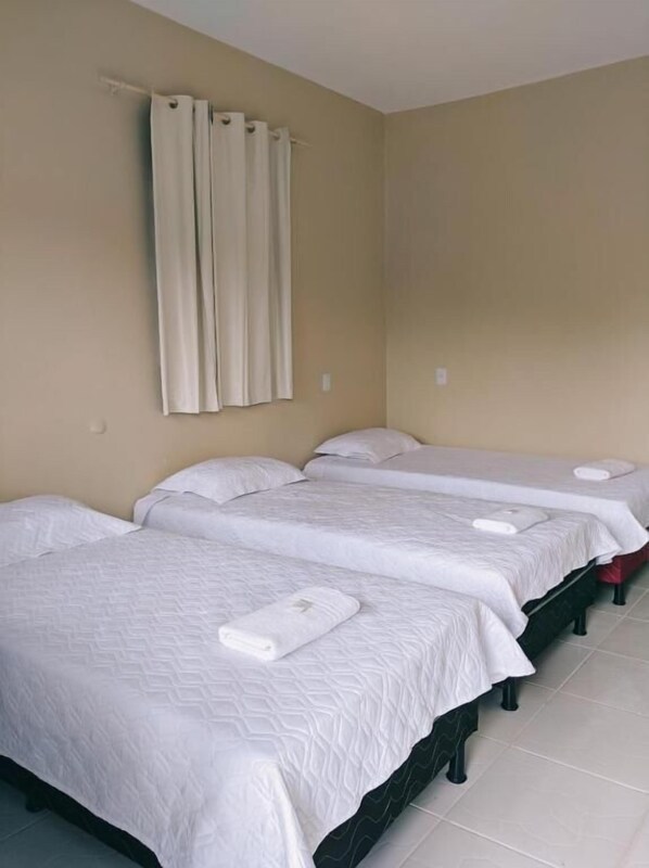 Una habitación de hotel con dos camas, paredes color beige y una cortina.