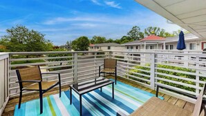 A covered outdoor area with a striped floor, two chairs, a table, and a blue umbrella. - 1st floor Condo near Lake MI, Saugatuck and  many attraction's.
Heated pool! (Douglas)