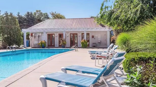 A poolside area with lounge chairs, a building with a red roof, and a clear blue sky. - 1st floor Condo near Lake MI, Saugatuck and  many attraction's.
Heated pool! (Douglas)