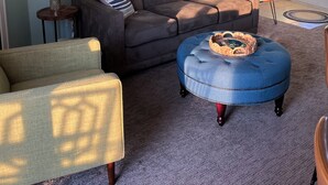 A living room with a sofa, ottoman, and armchair, a clock, and artwork on the wall. - 1st floor Condo near Lake MI, Saugatuck and  many attraction's.
Heated pool! (Douglas)