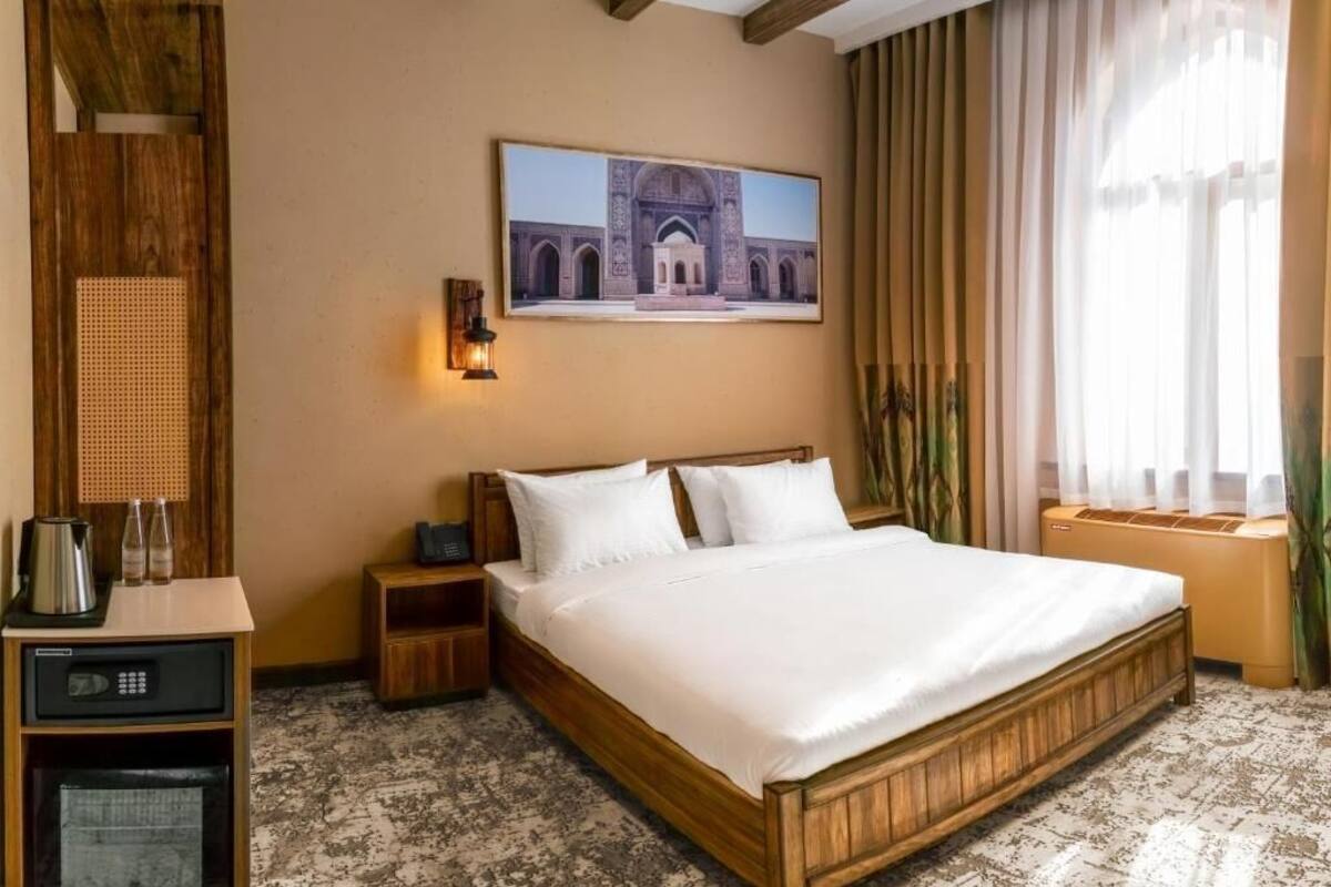 Ein Schlafzimmer mit einem Holzbett, einem Nachttisch, einem an der Wand befestigten Fernseher und einem Fenster mit Vorhängen.