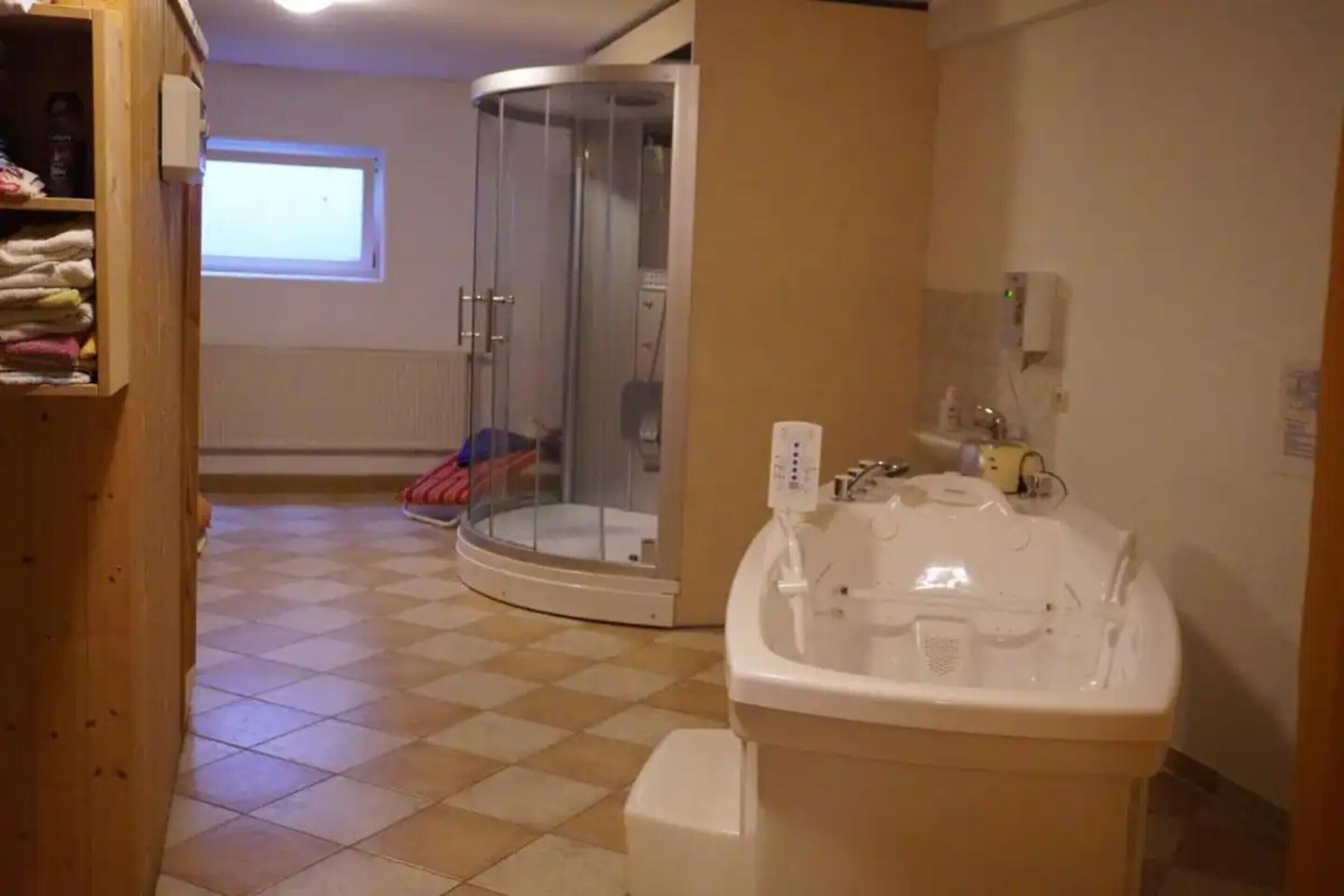 Un baño con ducha, bañera, ventana y un perchero para toallas.
