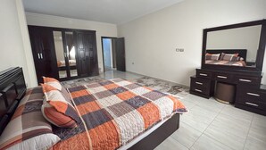 Une chambre à coucher avec un lit, une commode, un miroir et une armoire.