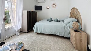 Une chambre à coucher avec un lit, une armoire, une télévision et une fenêtre avec des rideaux.