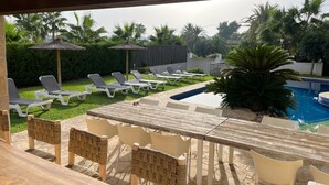 A poolside area with lounge chairs, a table, and a pool. - "Beautiful villa featuring a large swimming pool and landscaped gardens, privacy. (VC)