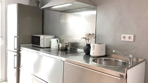 Moderni keittiö, jossa on ruostumattomasta teräksestä valmistetut kodinkoneet, mikroaaltouuni, vedenkeitin, leivänpaahdin ja pesuallas.