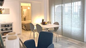 Moderni hotellihuone, jossa on ruokailutila, sänky ja suuri ikkuna, josta on näkymä.
