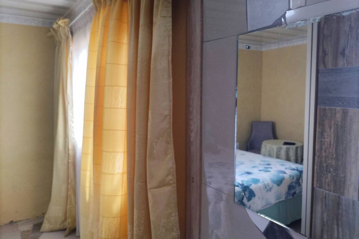 A room with a bed, a mirror, and curtains.