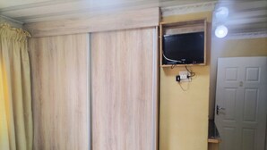A room with a bed, a wardrobe, a television mounted on the wall, and a door. - Lethabo Mountain View Guest House Cheap  (Maluti a Phofung)