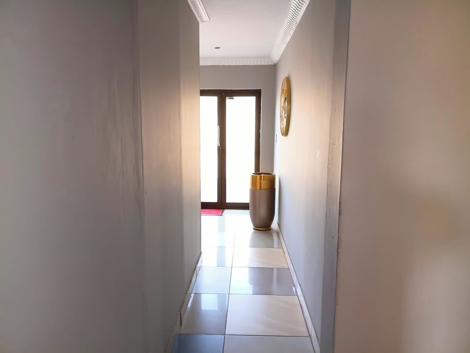 A hallway with a tiled floor leading to a door with a glass panel.