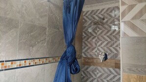 A shower with a blue curtain, tiled walls, and a geometric patterned wall design. - Lethabo Mountain View Guest House Cheap  (Maluti a Phofung)