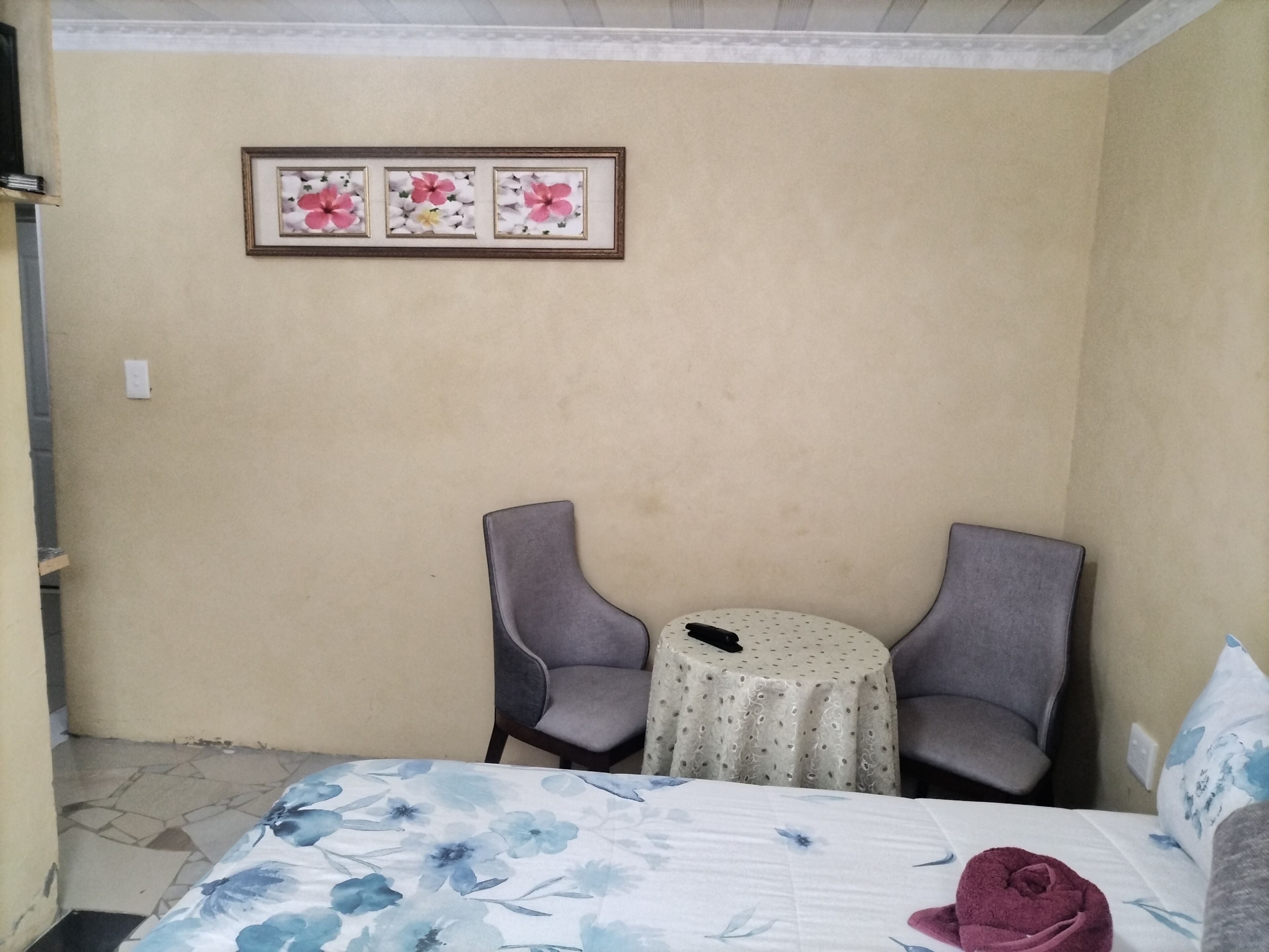 Una stanza con un letto, due poltrone, un tavolino rotondo e un quadro appeso al muro.