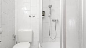 Een badkamer met toilet, douche en bad.