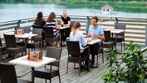 A group of people dining at an outdoor restaurant with a view of a lake and forest. - Bernsteinsee Home and Ferien Small Forest Chalet (Sassenburg)