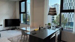 Eine moderne Küche mit einer großen Kochinsel, einer integrierten Waschmaschine und einem Fernseher auf der linken Seite.