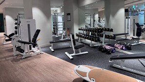 Ein Fitnessraum mit Kraftgeräten, Kurzhanteln und einer Bank.