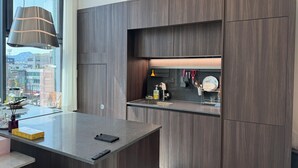 Eine moderne Küche mit dunklen Holdelementen, einer eingebauten Kochinsel und einem Fenster mit Blick auf die Stadt.